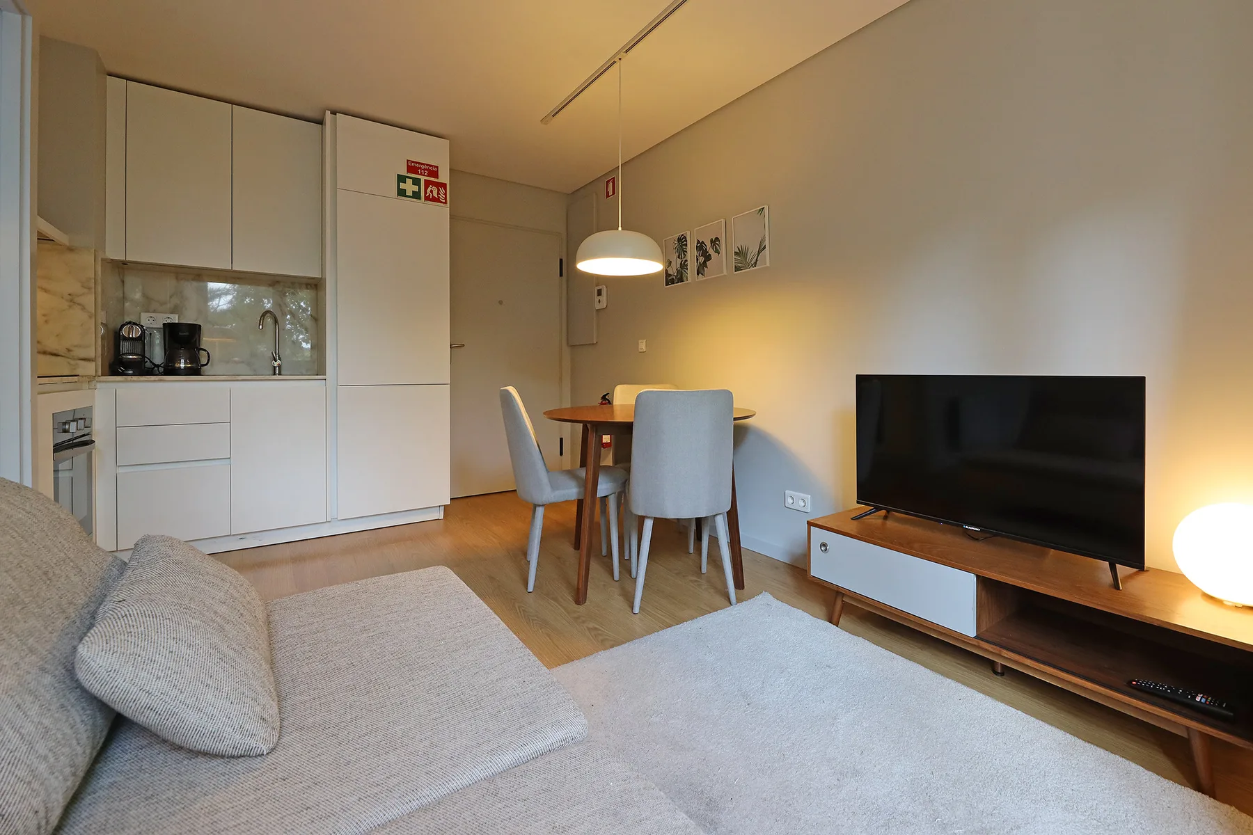 Zona de estar y comedor con televisor y una cocina compacta.
