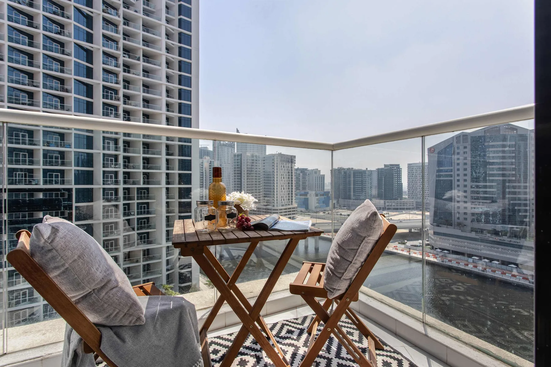 Una zona de estar en el balcón con una mesa pequeña ofrece vistas del horizonte urbano.