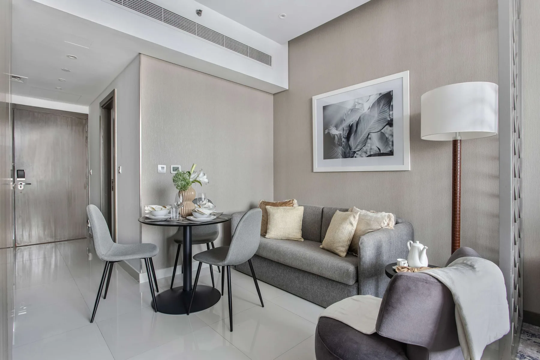 Una sala de estar moderna con un sofá gris y una pequeña mesa de comedor.