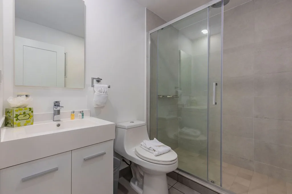 Your private bathroom is beautifully appointed with a modern vanity, spacious walk-in shower, and plush towels ready for your stay.