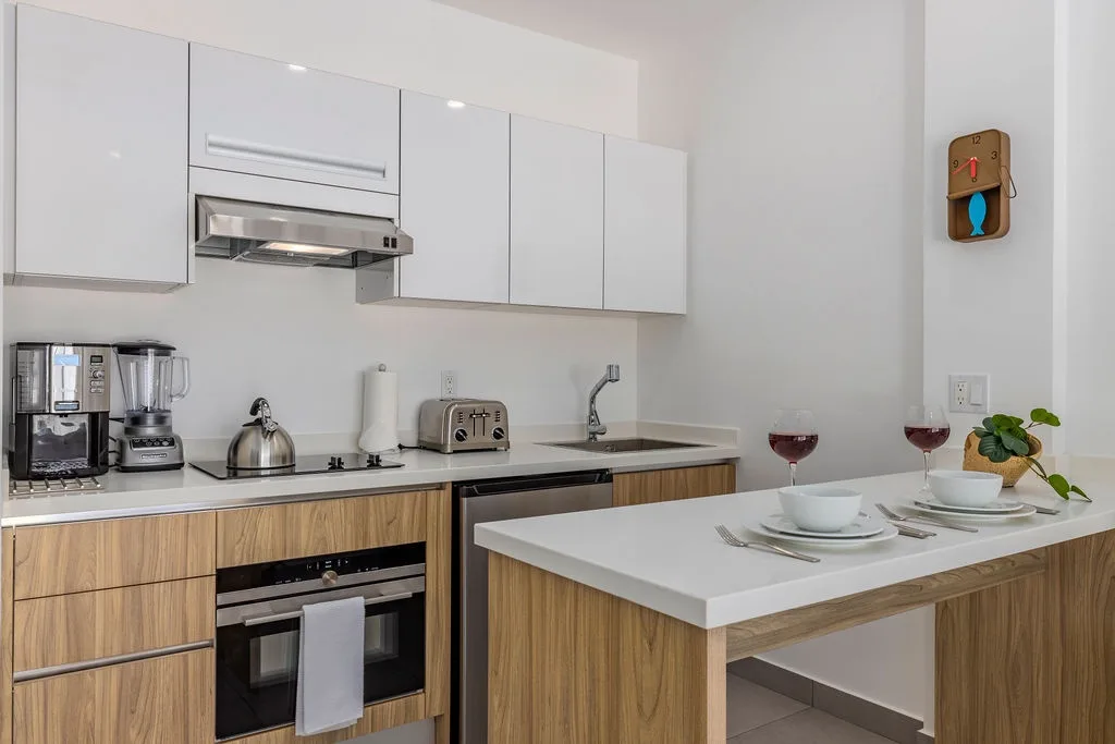 Your modern kitchen features sleek white cabinetry, stainless appliances, and a bright breakfast bar—perfect for preparing meals and savoring morning coffee together.