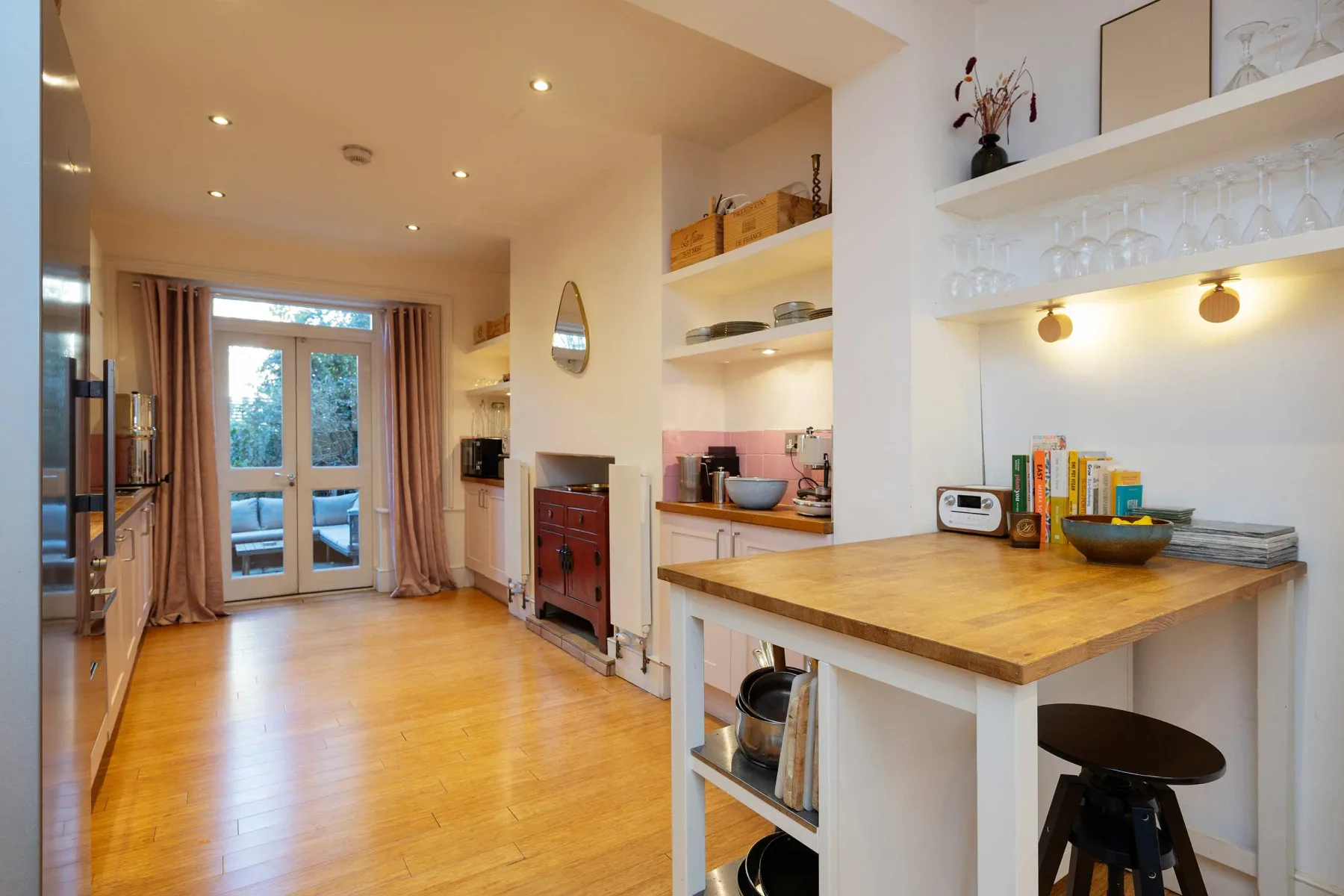 Una cocina luminosa con una encimera de madera y comedor junto a puertas de cristal.