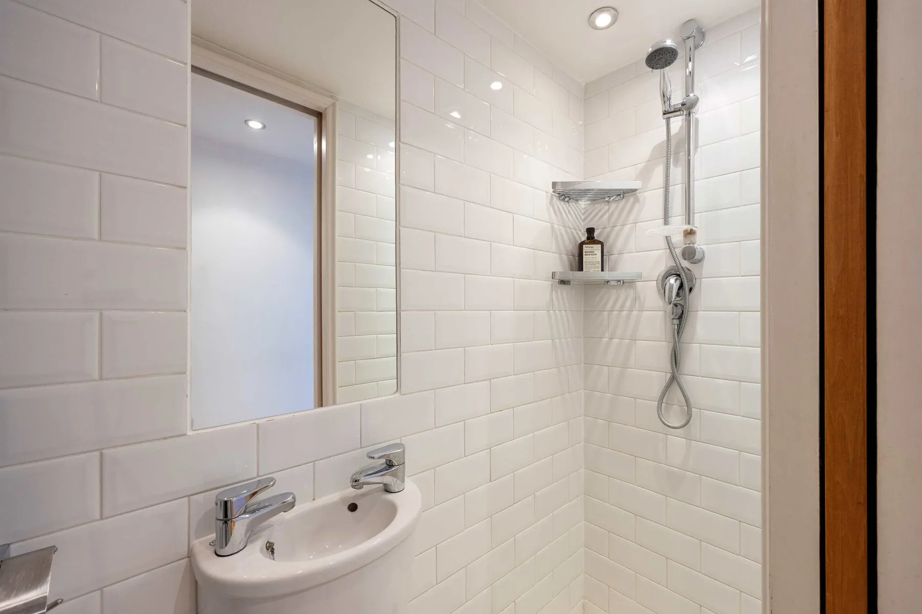 Un baño alicatado con lavabo, espejo y ducha.