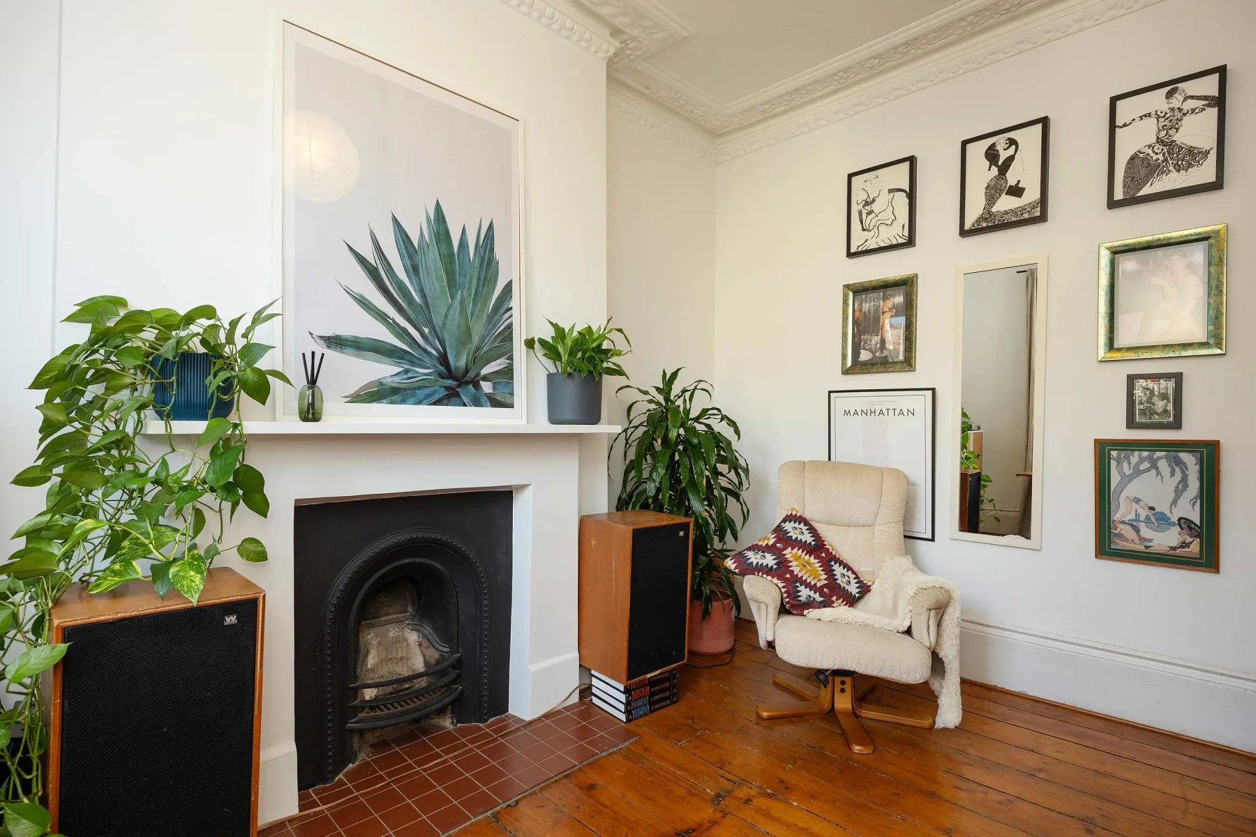 Una sala de estar con chimenea, cuadros enmarcados y un sillón acolchado.