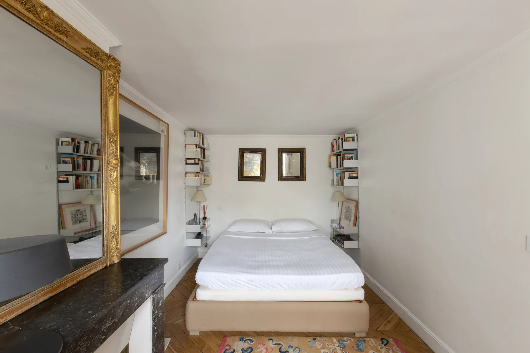 Un dormitorio luminoso con una cama bien hecha entre estantes empotrados.