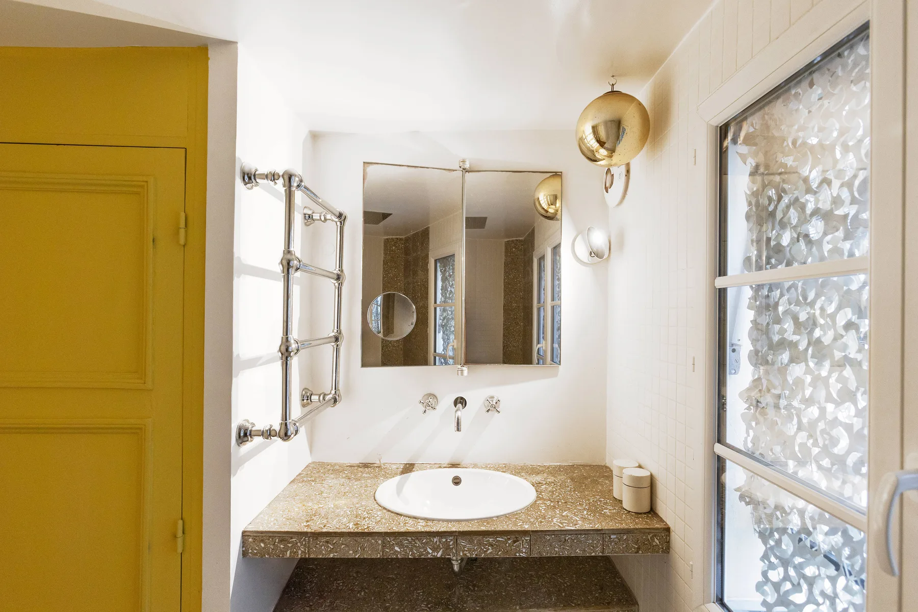 Un baño luminoso con un espejo de pared sobre el lavabo.