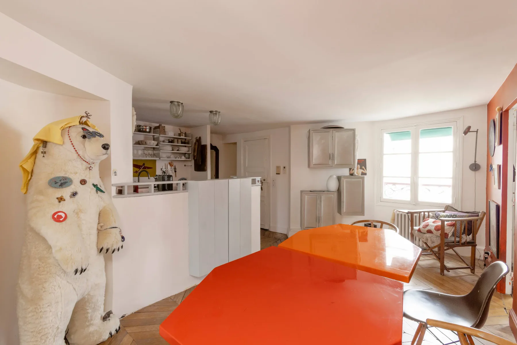 Una sala luminosa con una mesa naranja brillante y una ventana.