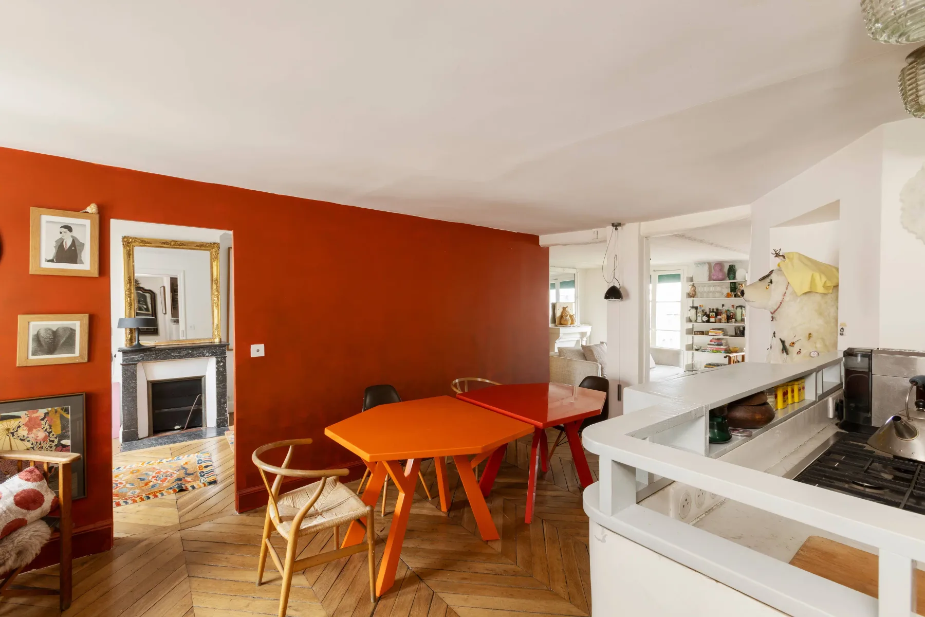 Comedor con una mesa naranja junto a una pared roja.