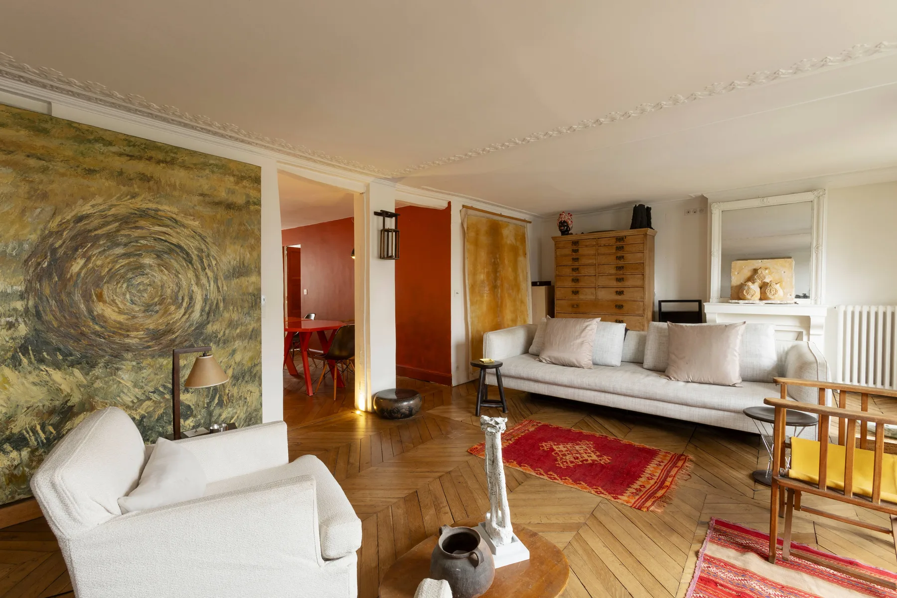 Una sala luminosa con asientos blancos, alfombras coloridas y cuadros grandes.