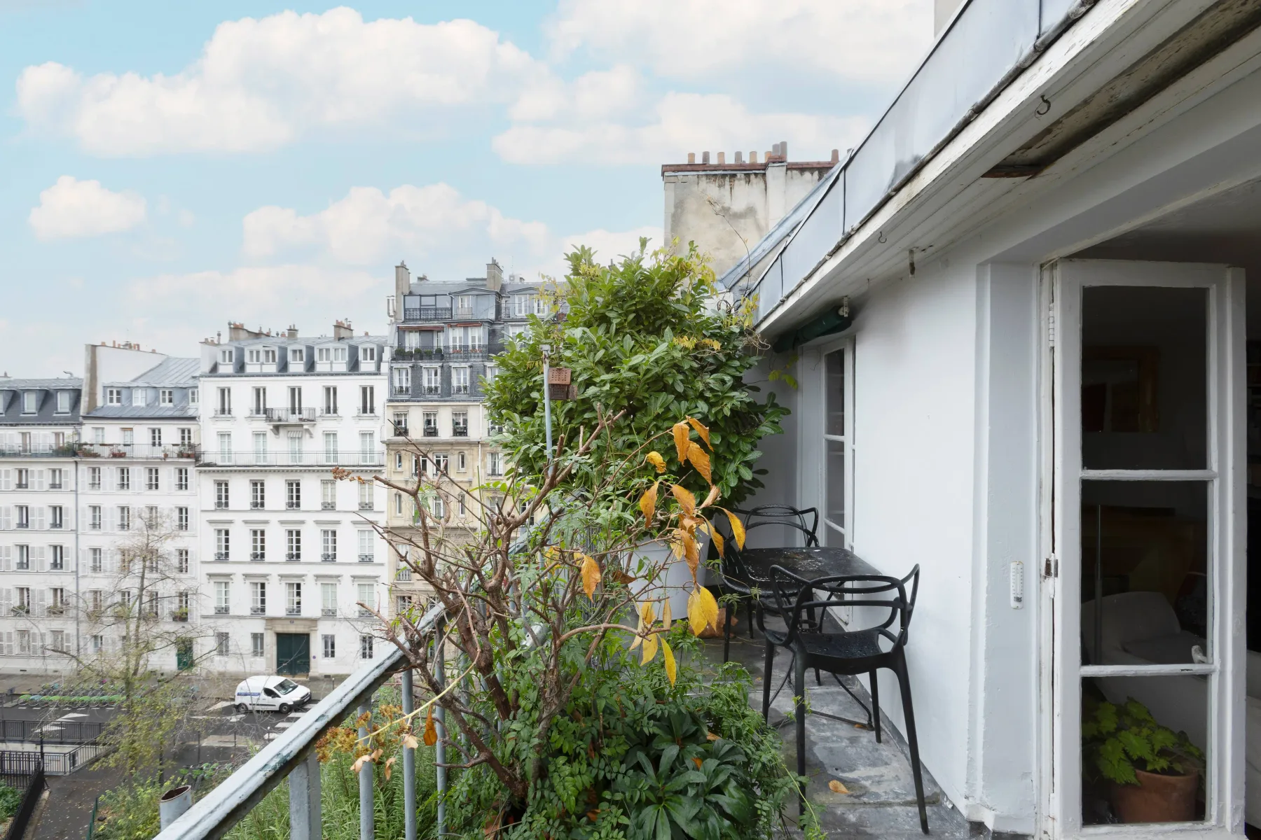 Una terraza en la azotea con plantas, asientos y vistas a edificios cercanos.
