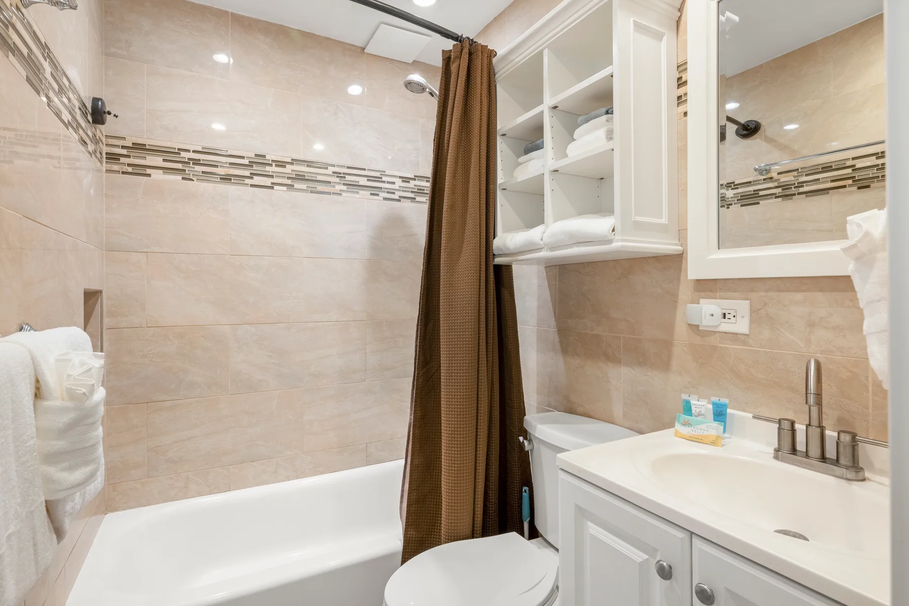 Un baño con bañera, cortina de ducha y lavabo con mueble.