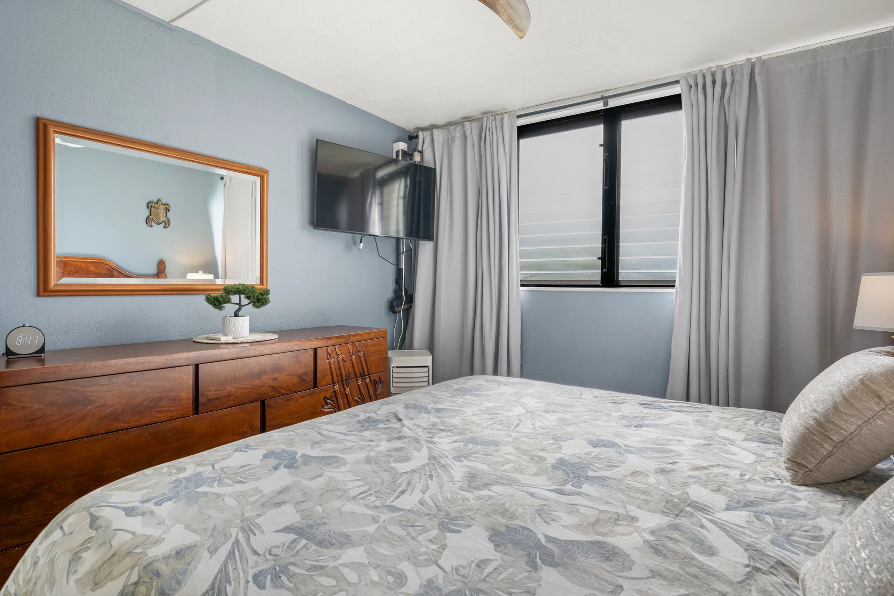 Un dormitorio con una cama, una cómoda de madera y una ventana con cortinas.