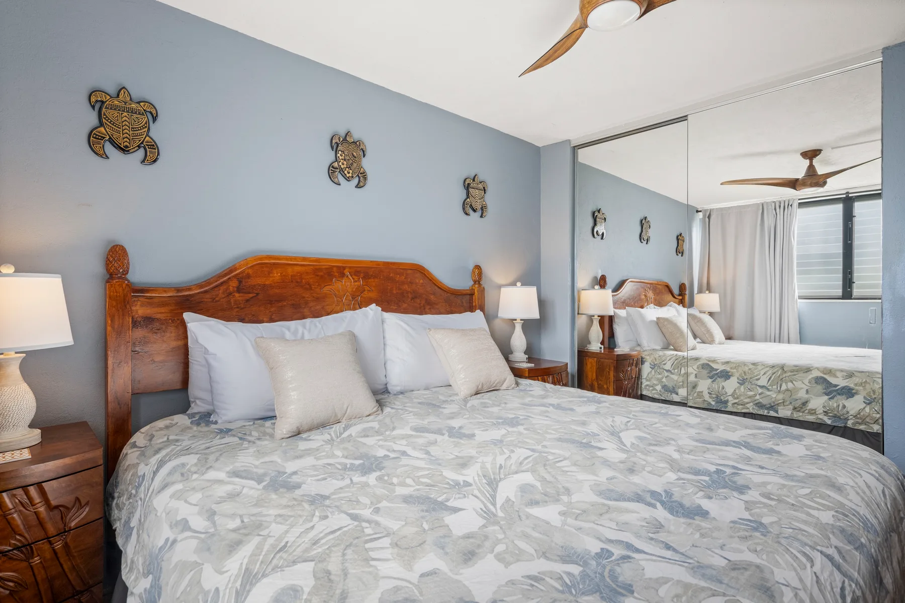 Un dormitorio con cama de madera, ropa de cama clara y puertas de armario con espejo.