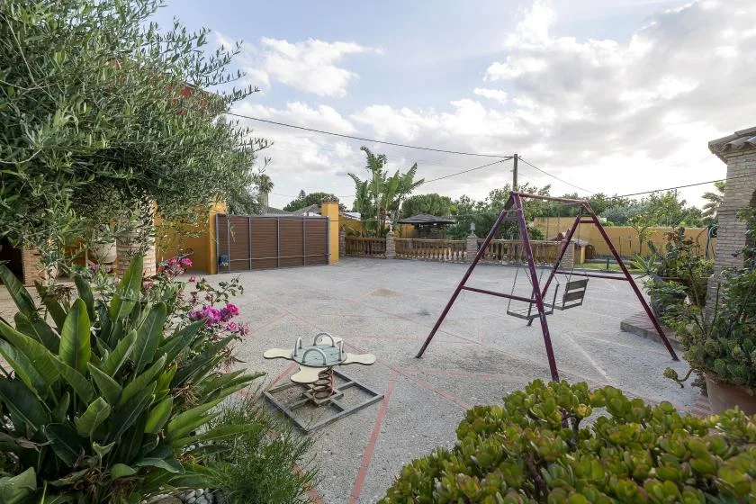 An outdoor play area with a swing set and paved ground.
