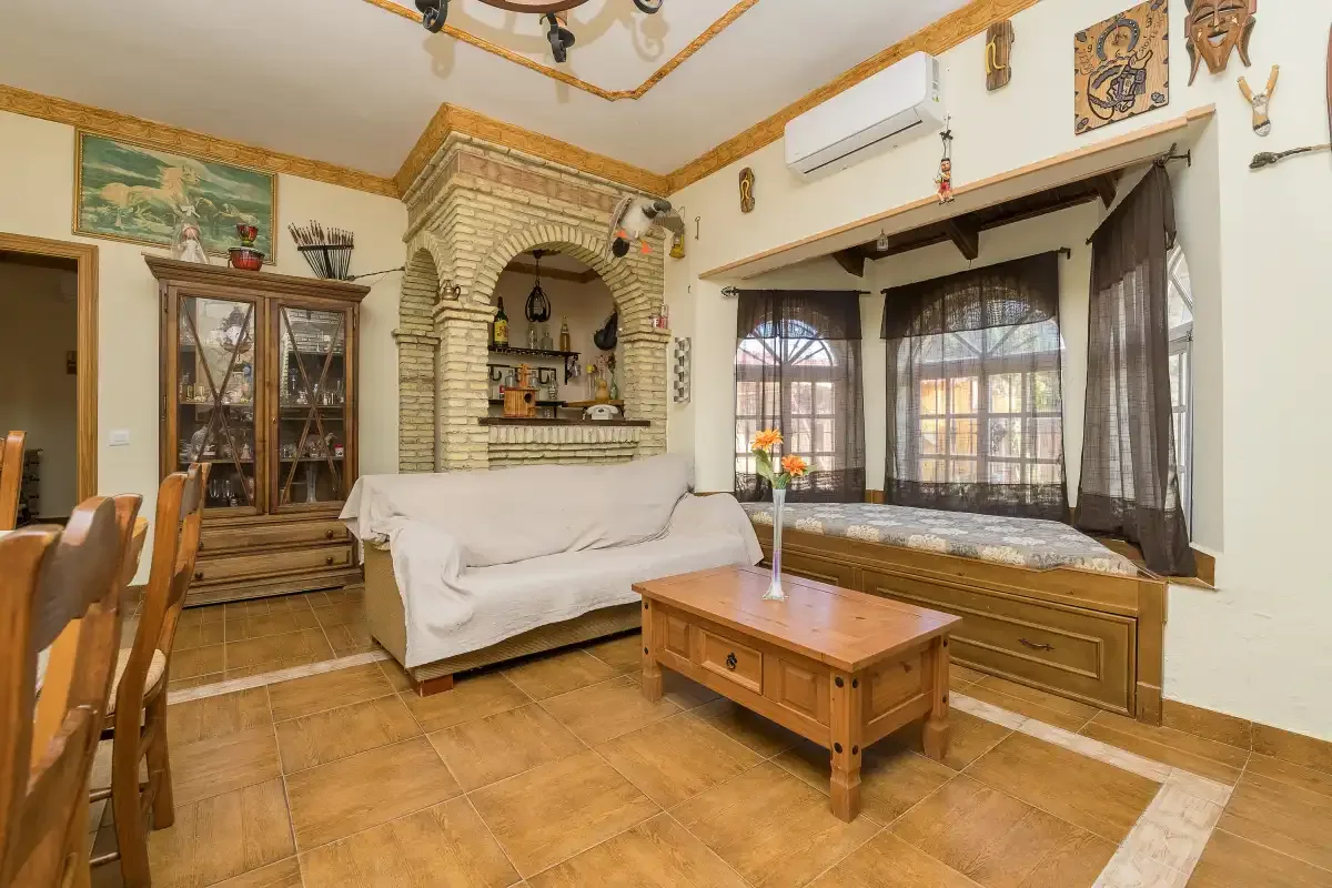 A living room with seating, a wooden coffee table, and large curtained windows.