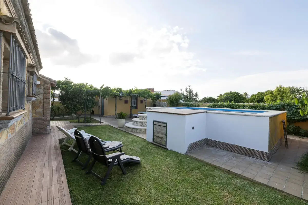 A garden patio with outdoor seating and a swimming pool beside the house.