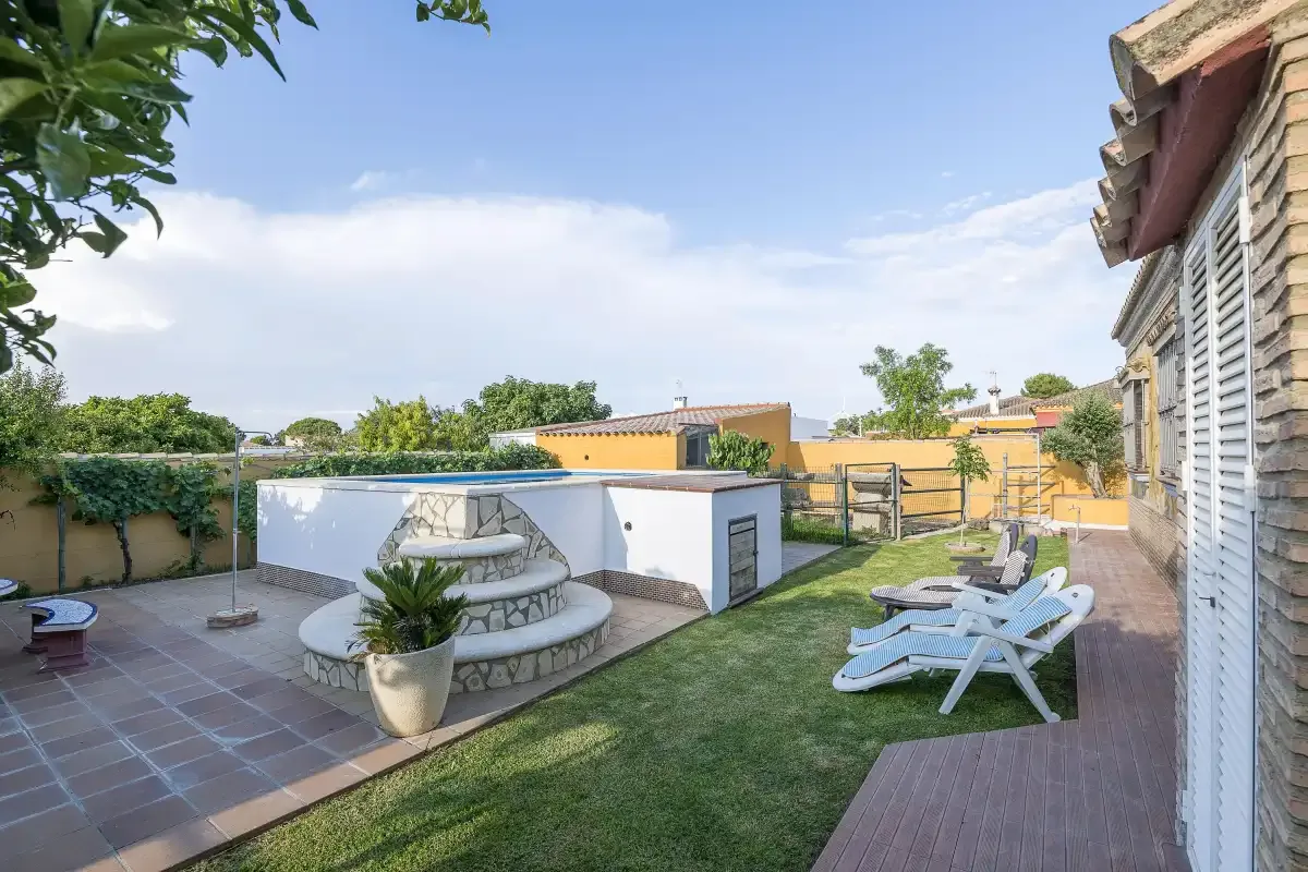 An outdoor patio and lawn with a small circular pool and lounge seating.