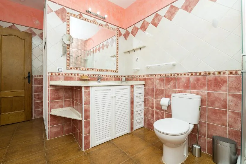 A bathroom with a tiled vanity, mirror, and toilet.