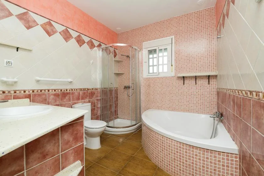 A bathroom with a curved bathtub, shower, and tiled walls.