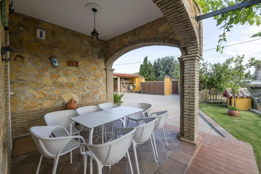 A stone patio dining area opens onto a garden and paved courtyard.