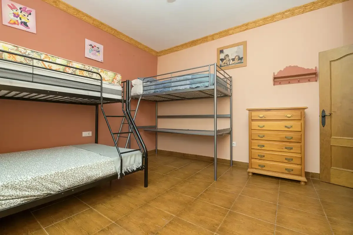 A bedroom with bunk beds, a dresser, and a tiled floor.