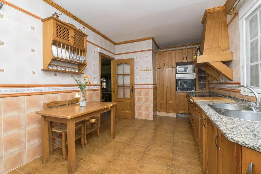 A kitchen with wooden cabinets, a dining table, and a countertop sink.
