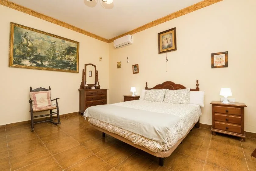 A bedroom with a large bed, wooden bedside tables, and framed wall art.