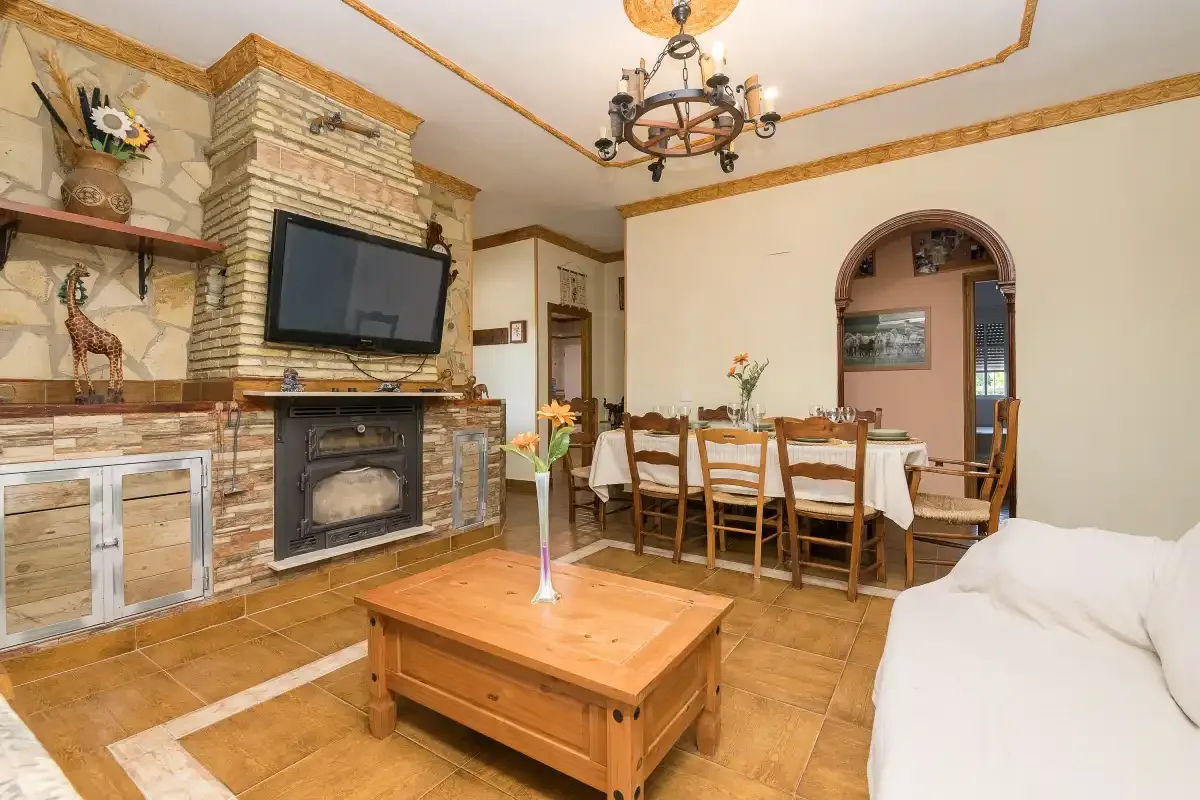 A living and dining room with a fireplace, television, and table.