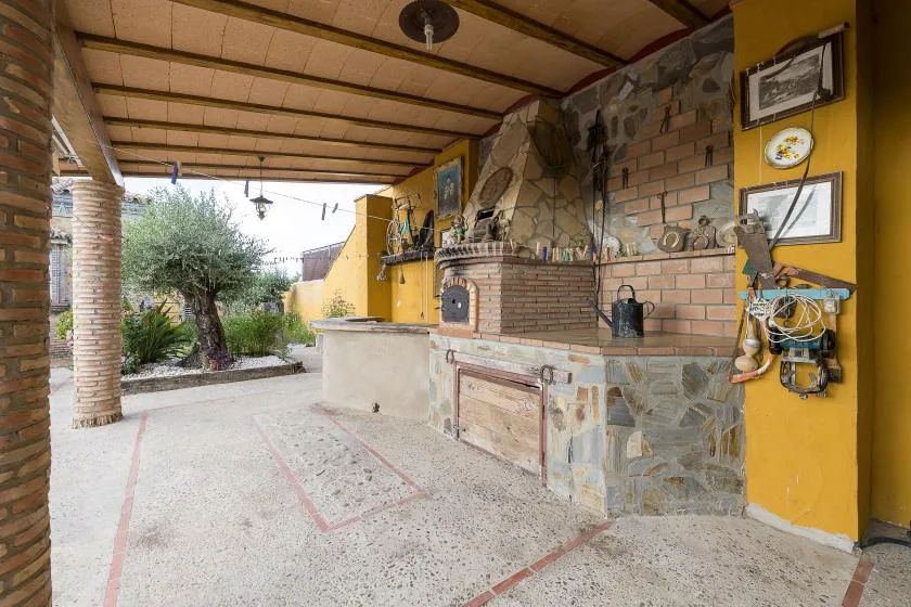 A covered outdoor patio features a brick cooking area and a broad open floor.