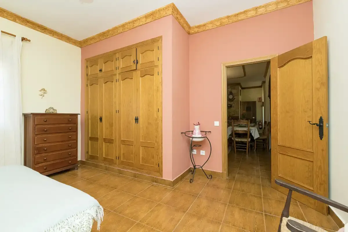 A bedroom with a large wooden wardrobe and an open doorway.