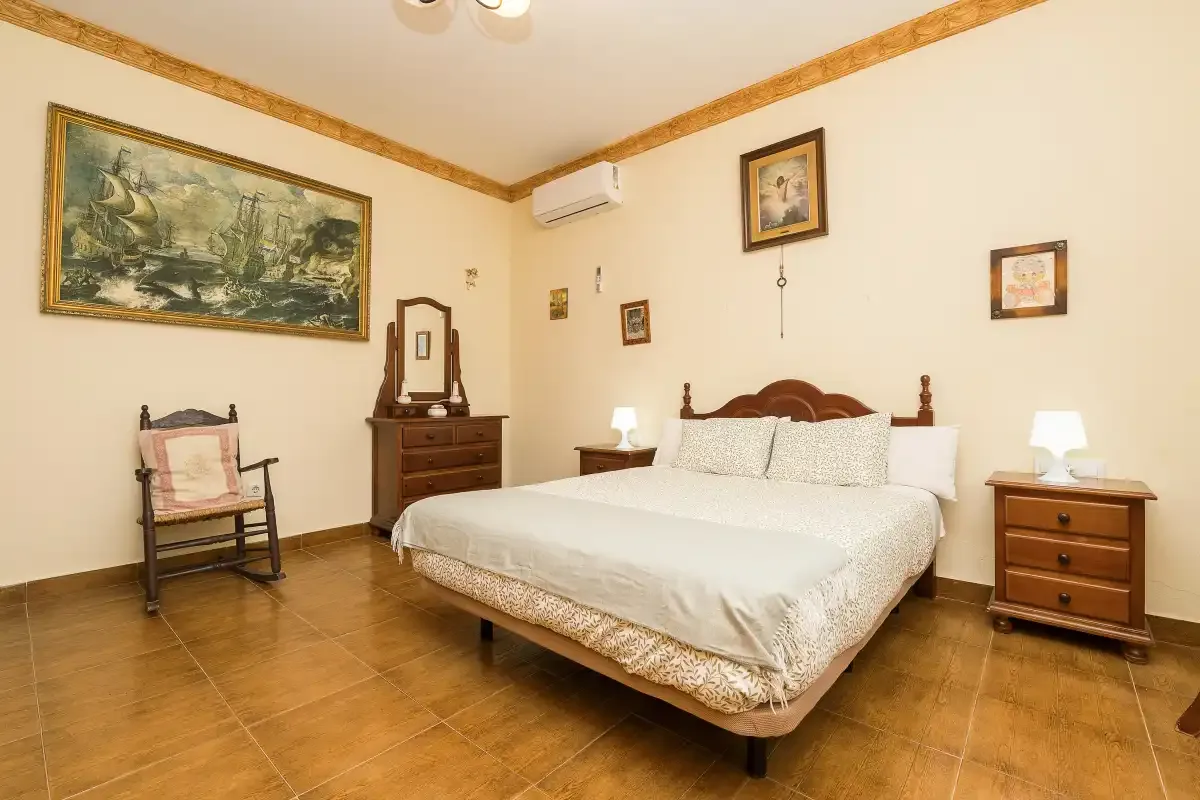 A bedroom with a large bed, bedside tables, and framed artwork.