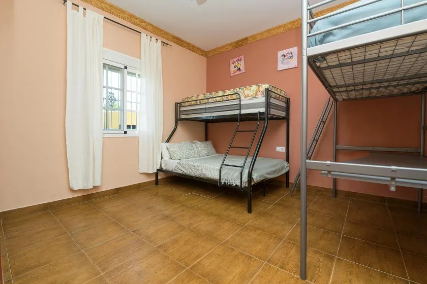 A bedroom with metal bunk beds, a window, and tiled flooring.
