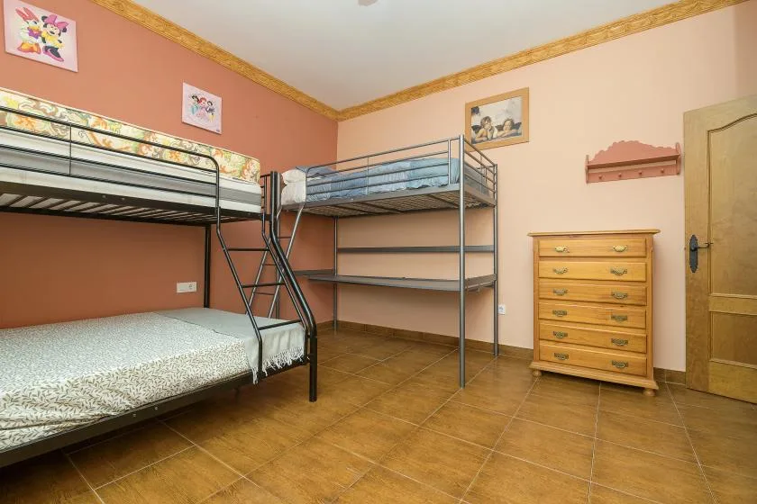 A bedroom with bunk beds and a wooden dresser.