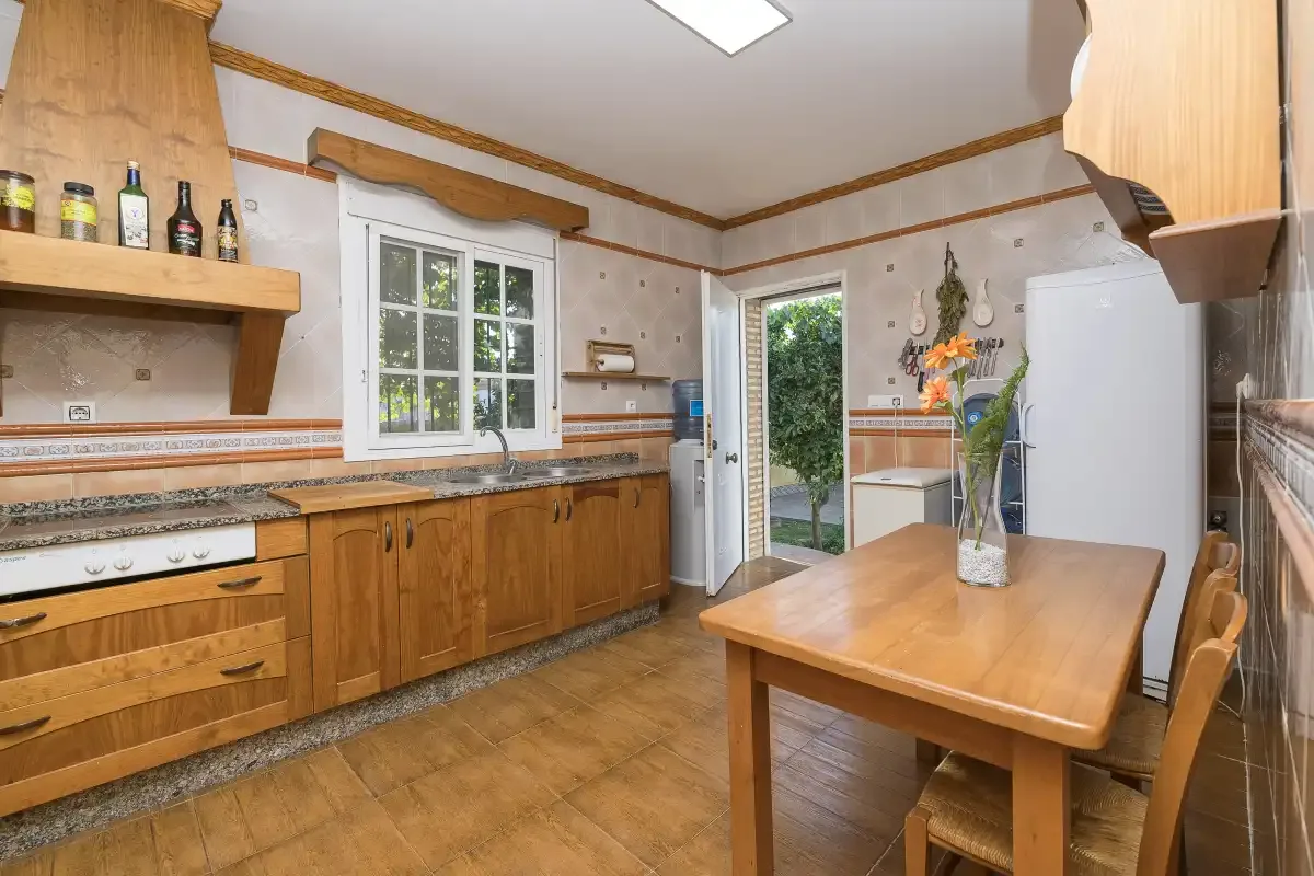 A kitchen with wooden cabinets, a countertop, and a dining table.