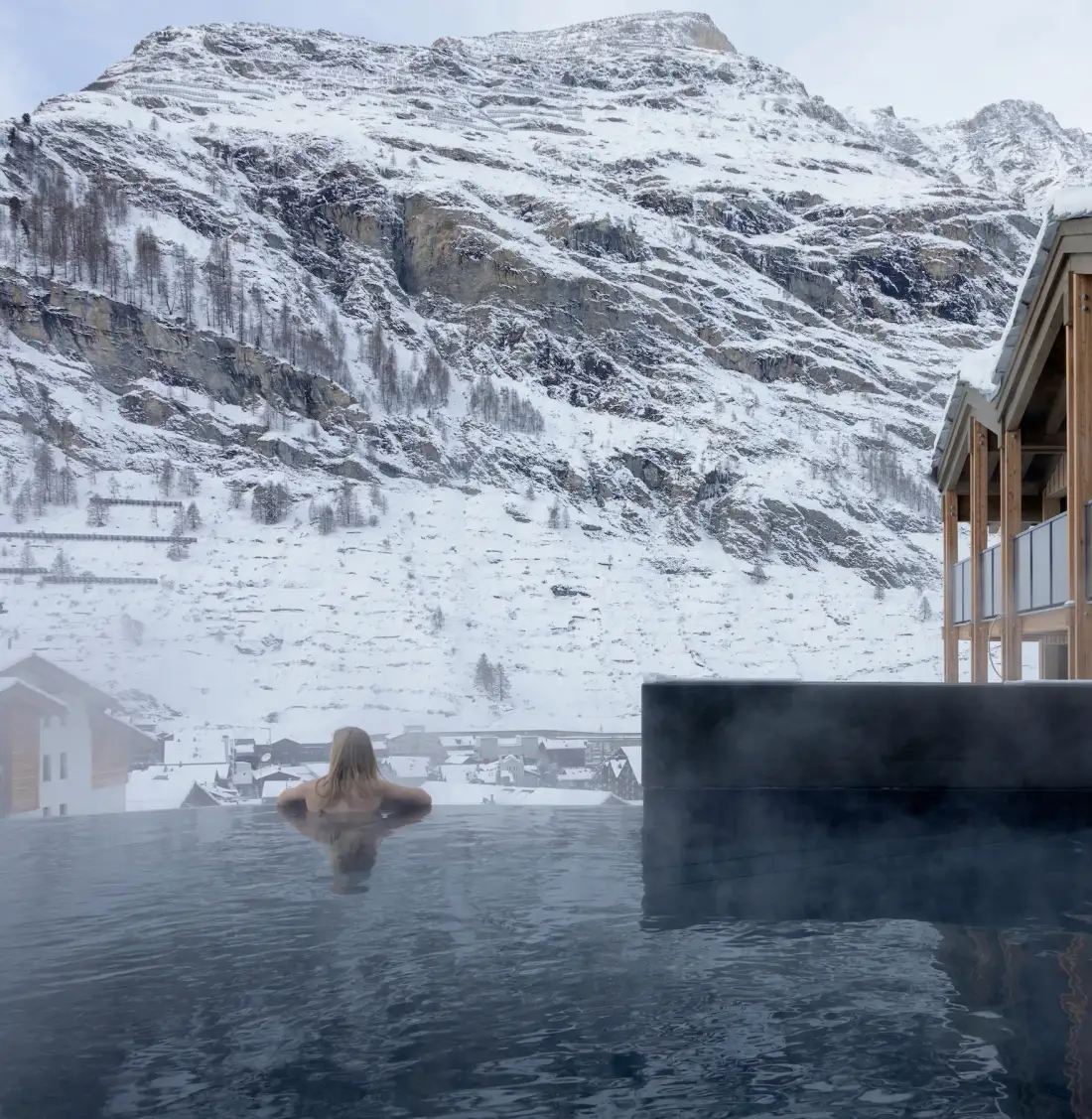 Huésped en el onsen de inspiración japonesa mirando hacia las montañas nevadas