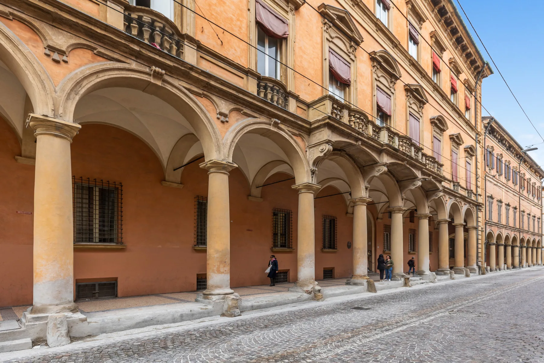 A street lined with historic buildings featuring arched porticoes and columns.