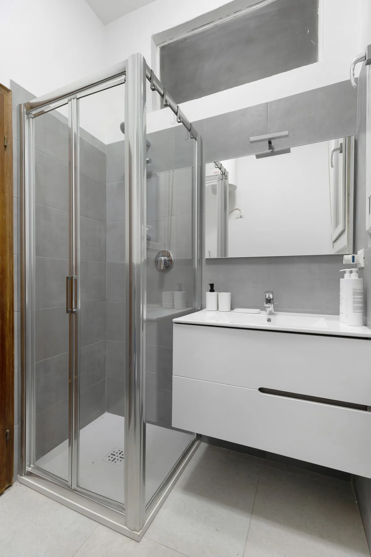 A modern bathroom with a glass-enclosed shower and a wall-mounted vanity.