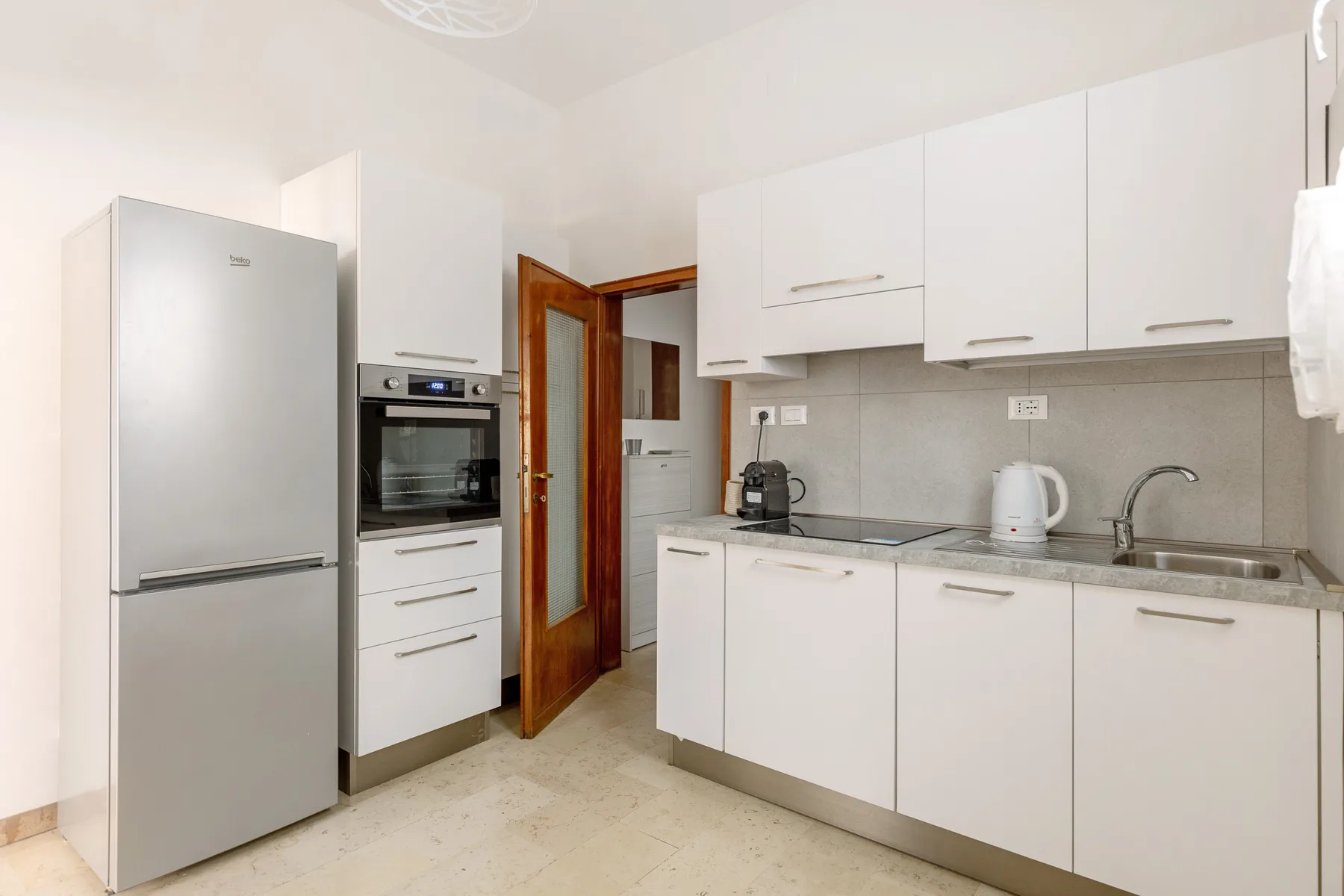 A bright kitchen with white cabinets, a refrigerator, and countertop appliances.