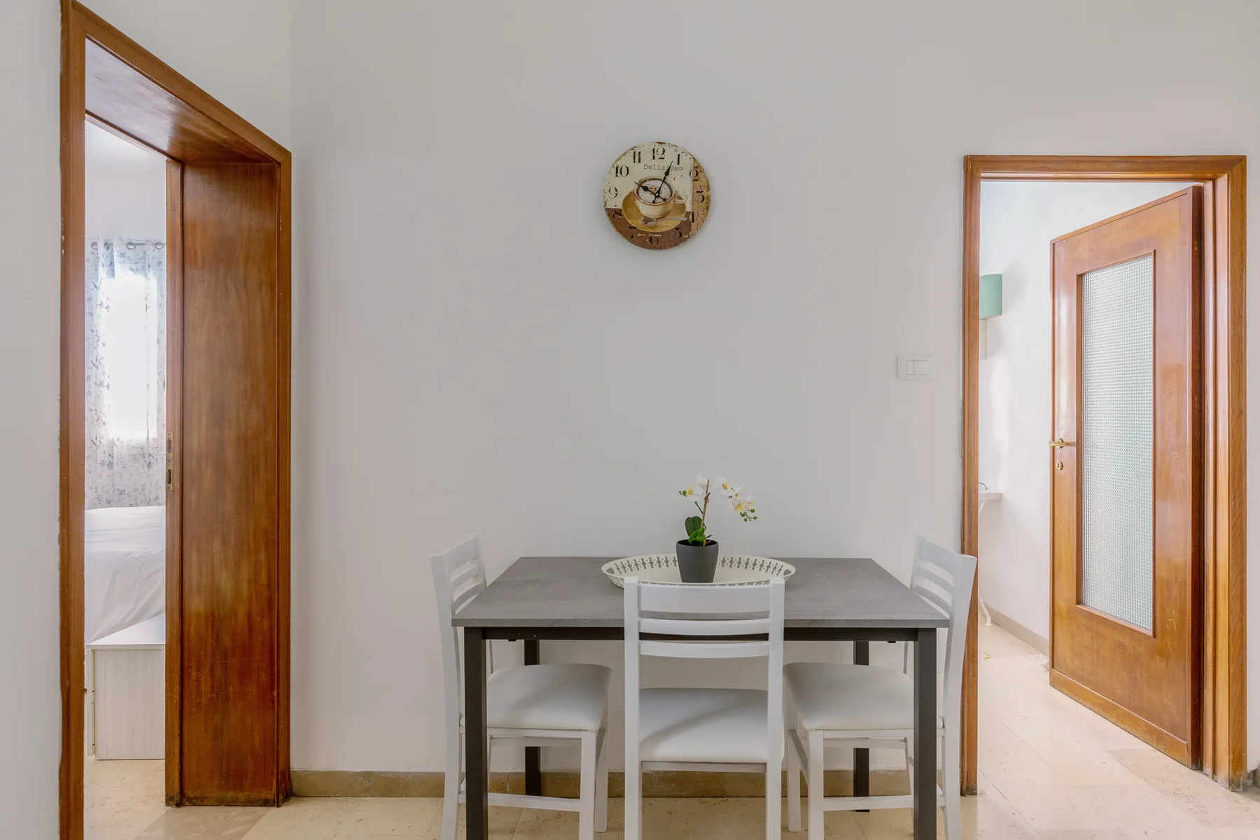 A dining area with a table and chairs beneath a wall clock.