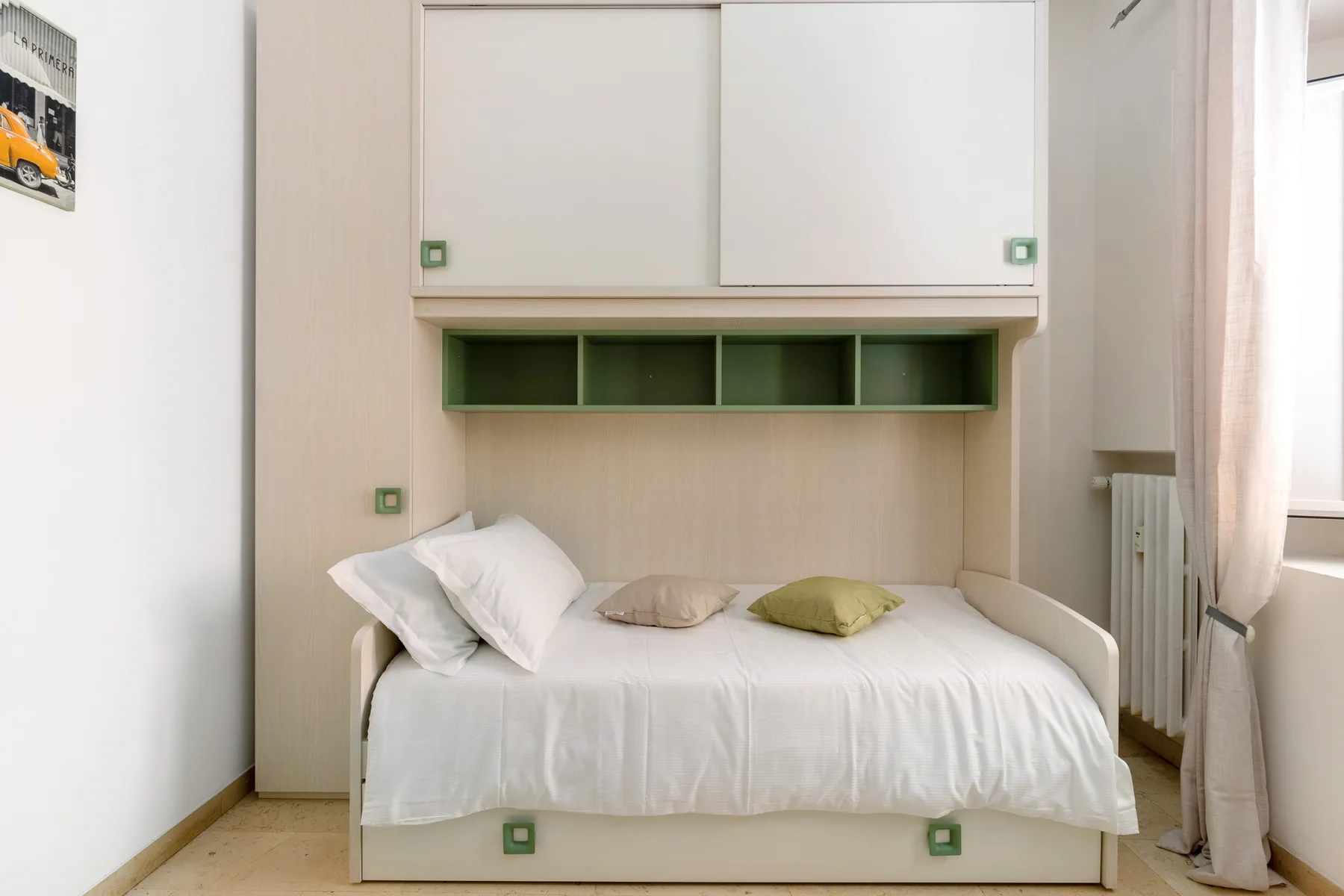 A bedroom with a bed beneath built-in shelving and storage cabinets.