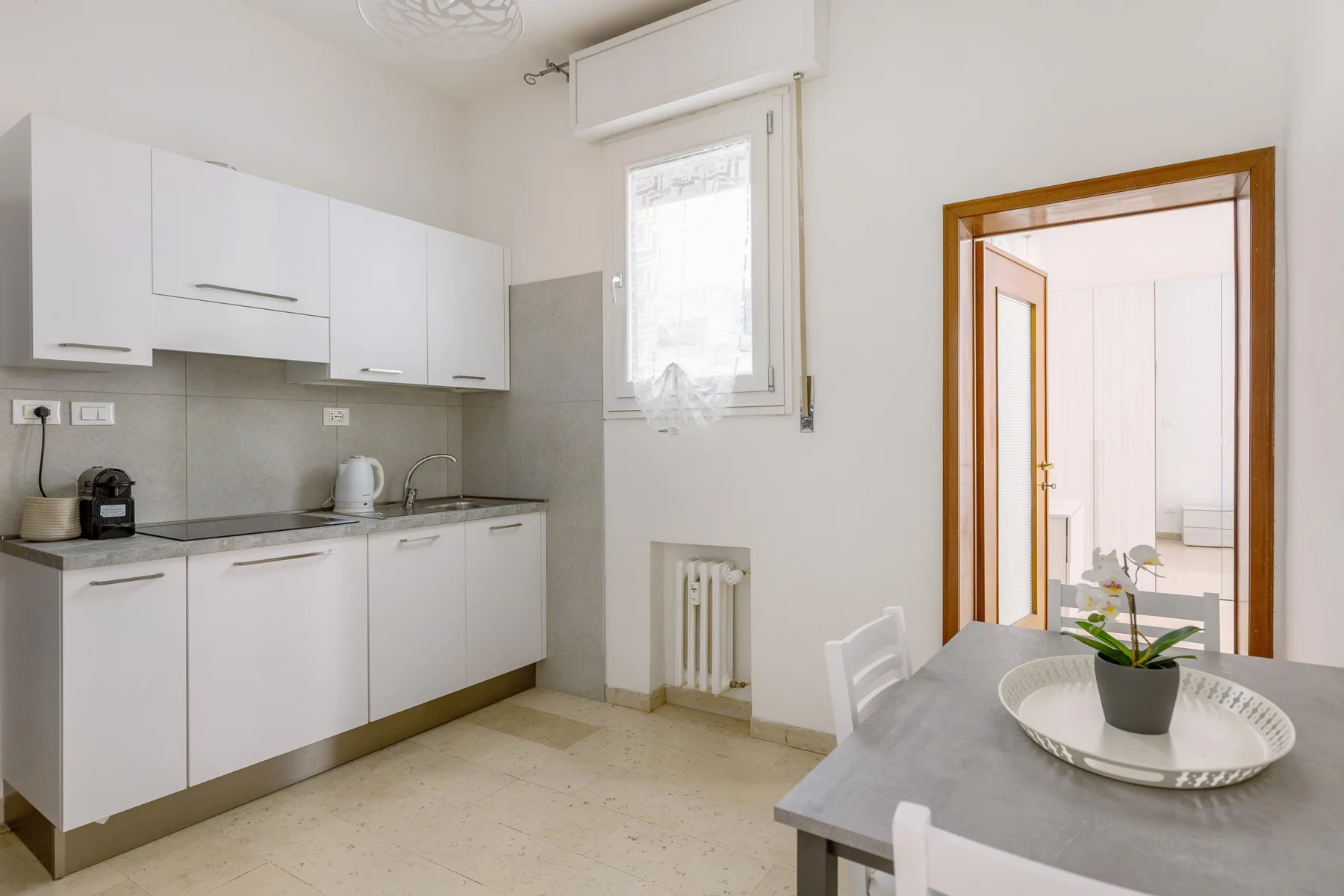 A bright kitchen with white cabinets and a dining table.