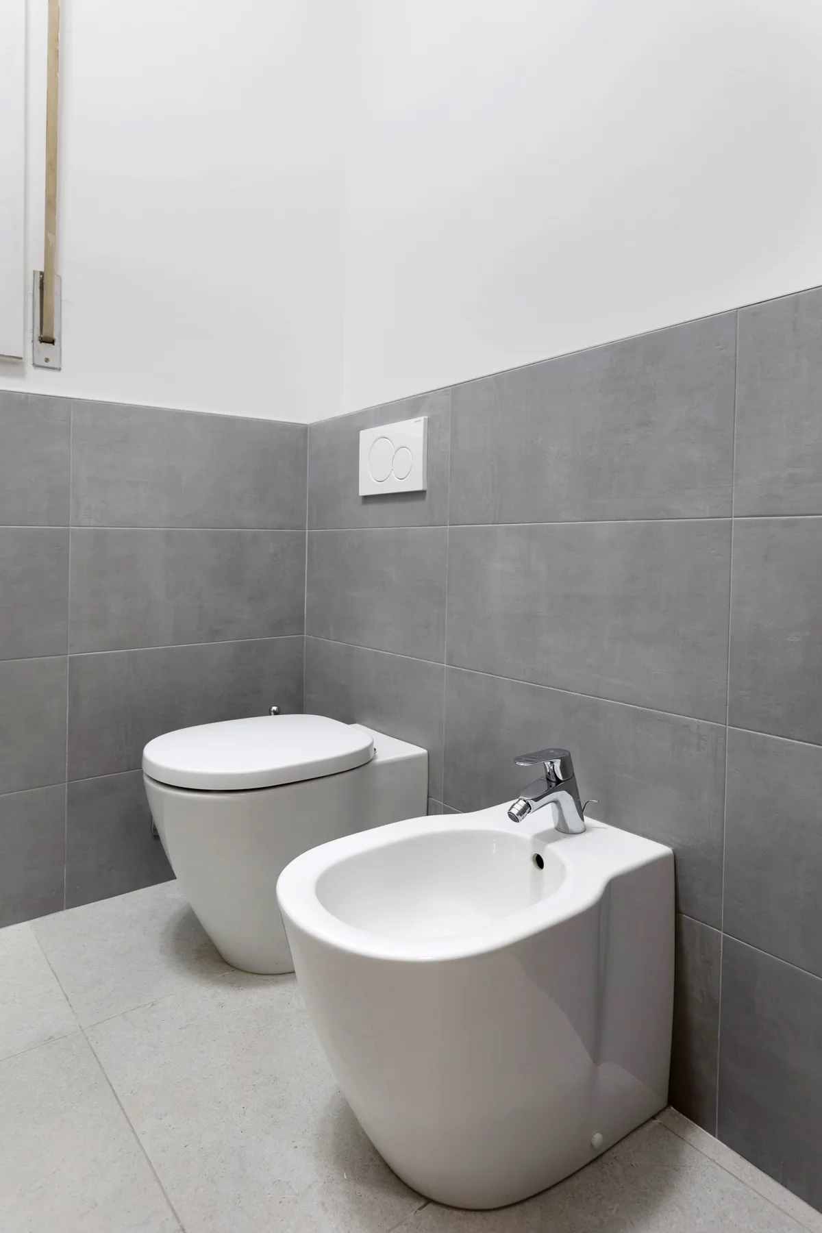 A tiled bathroom with a toilet and bidet.