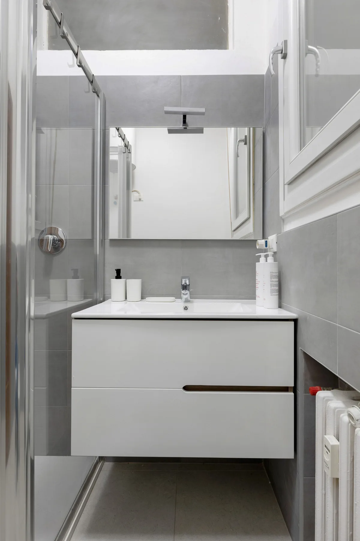 A bathroom vanity with a mirror and glass shower enclosure.