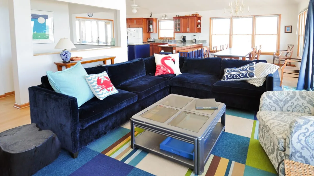 A living room with dark sectional seating around a glass coffee table.