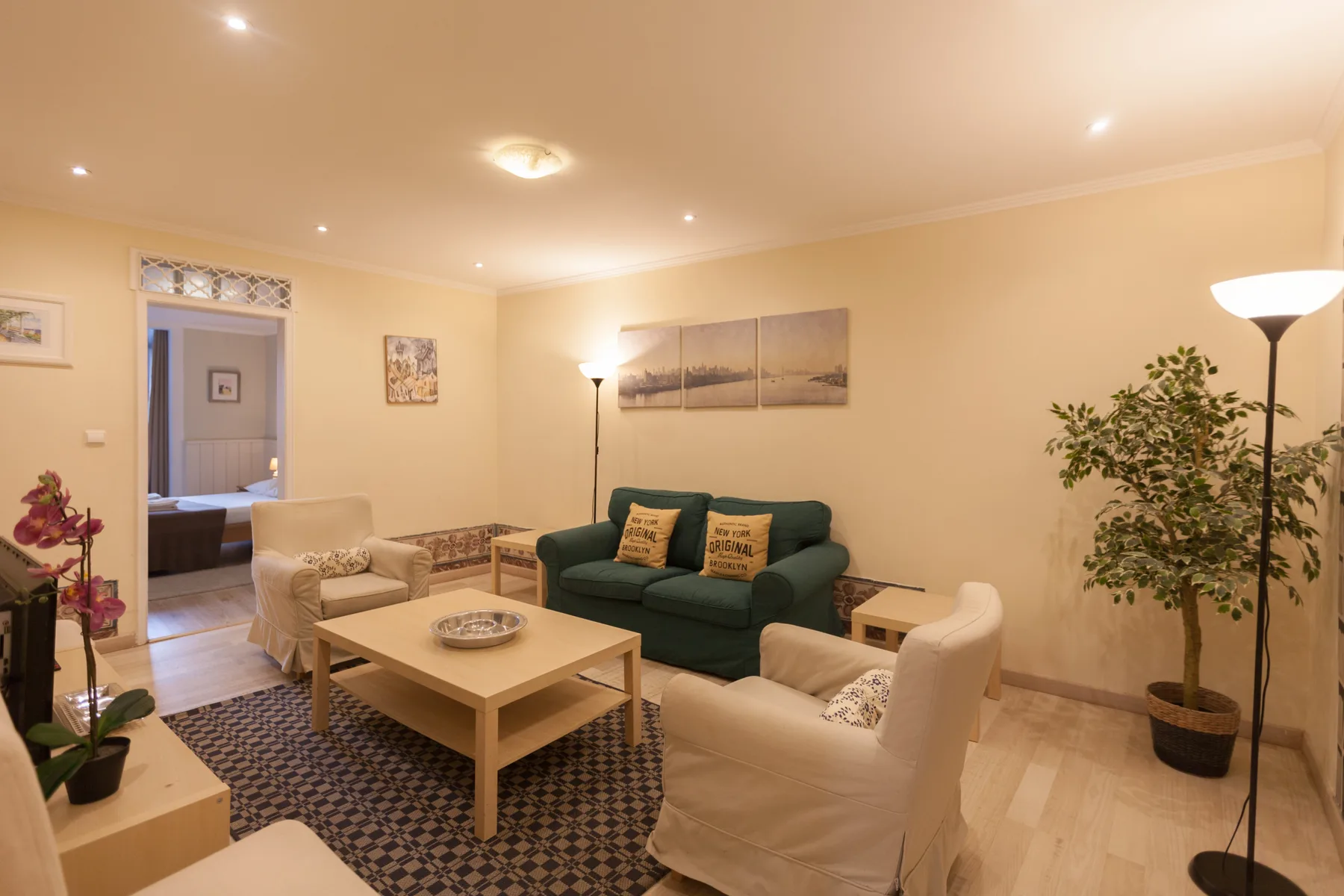 A living room with seating arranged around a coffee table and a potted plant.