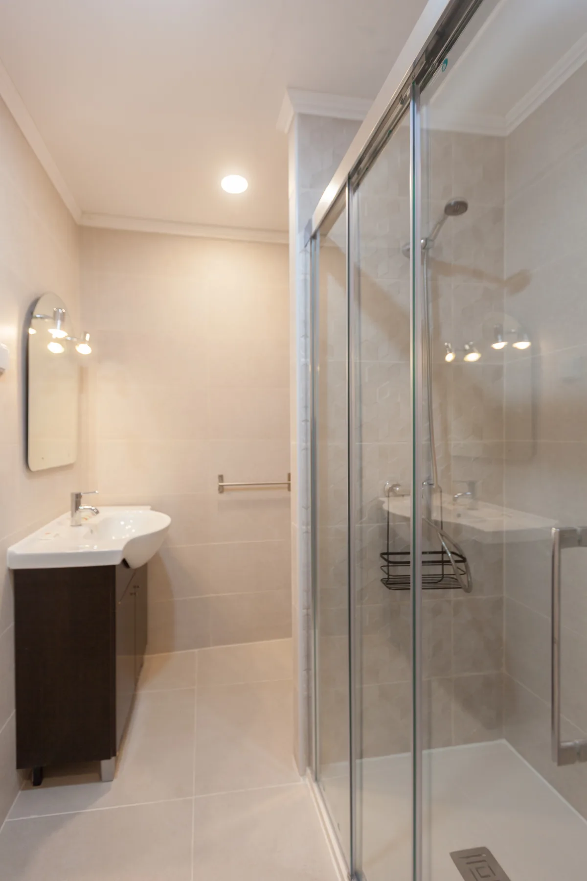 A bathroom with a sink and a glass-enclosed shower.
