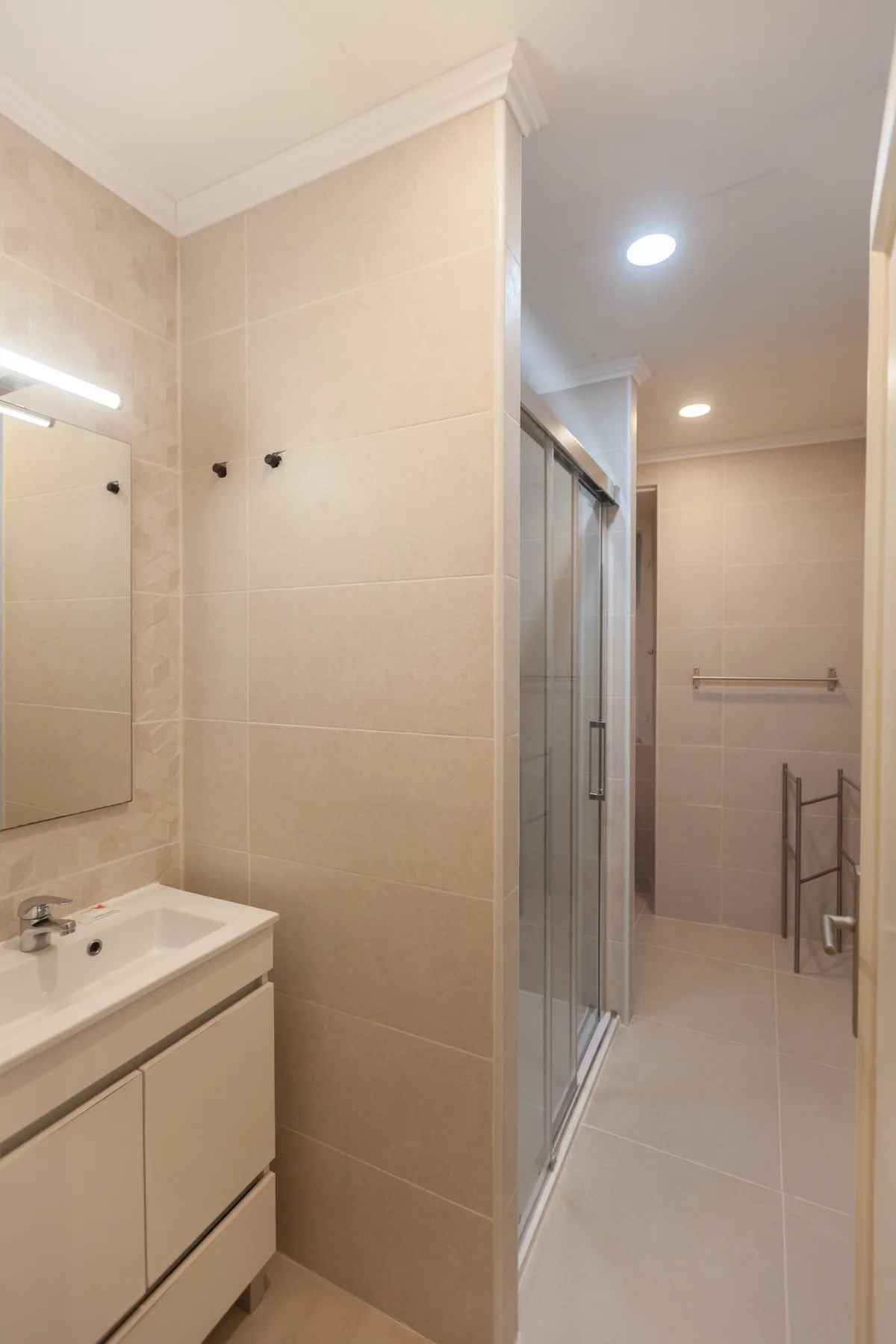 A tiled bathroom with a sink, mirror, and glass shower.