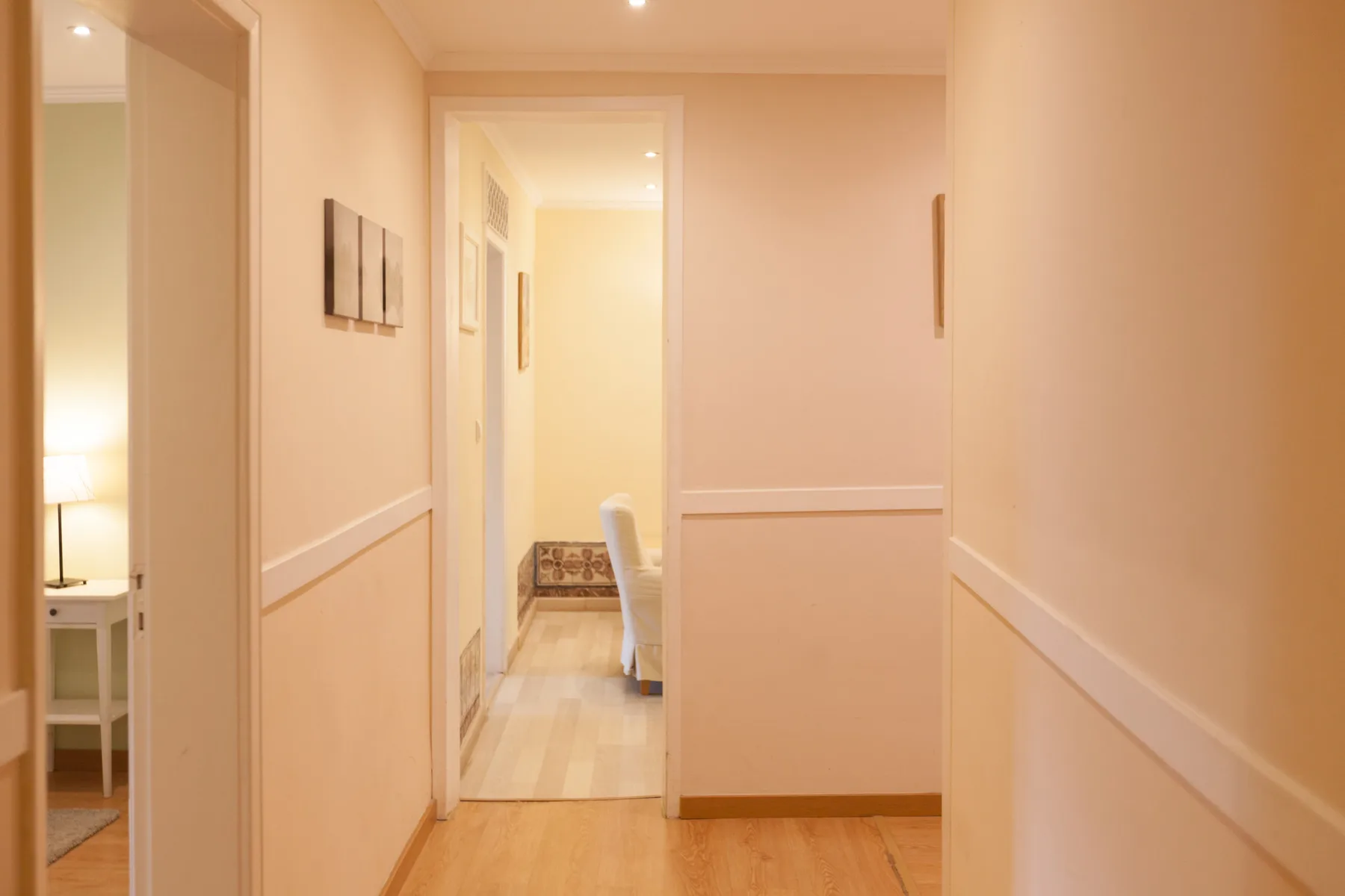 A softly lit hallway with doorways and pale walls.