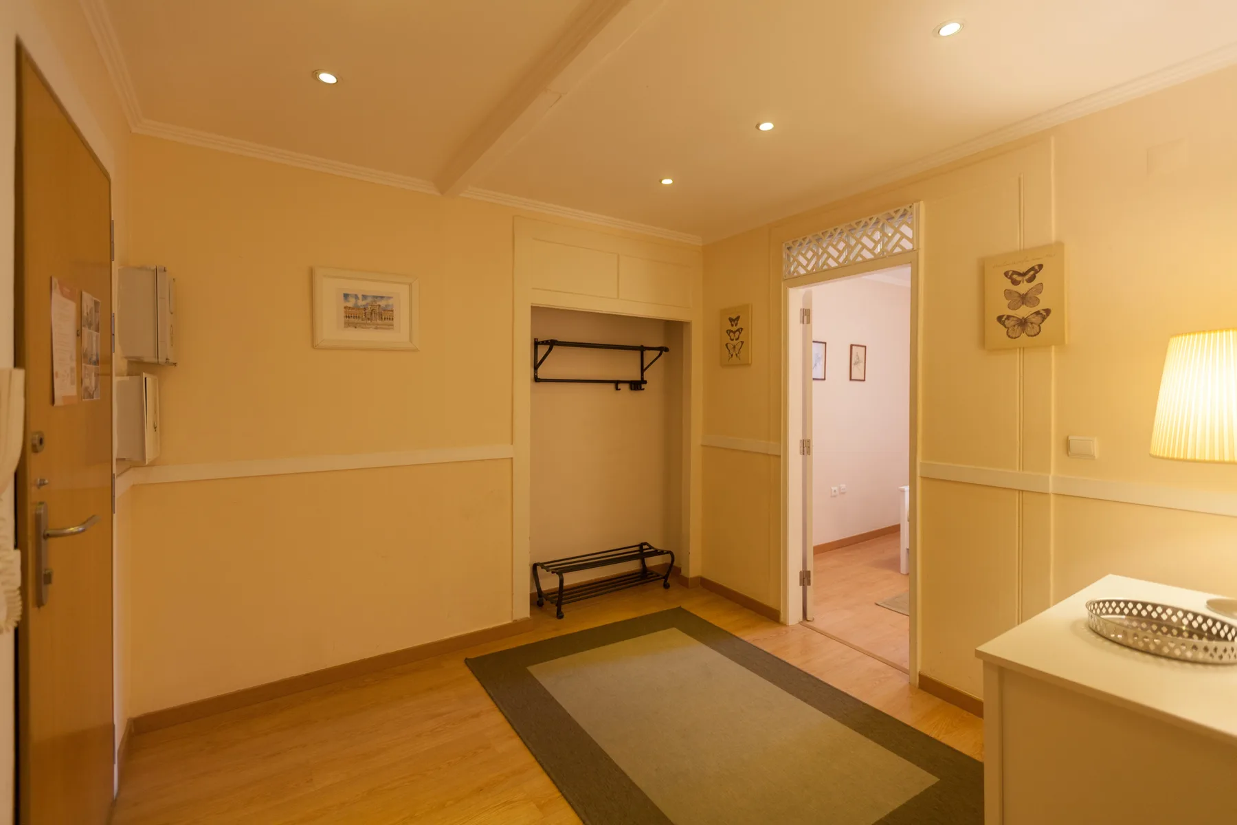 A warm-toned entry hall with a coat rack and a rug on the floor.