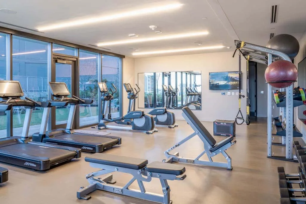 Un gimnasio con cintas de correr, bicicletas estáticas y equipos de entrenamiento con pesas.